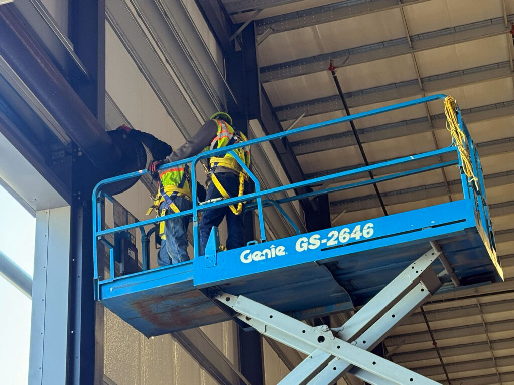 Technicians installing a tall commercial garage door from a Genie lift