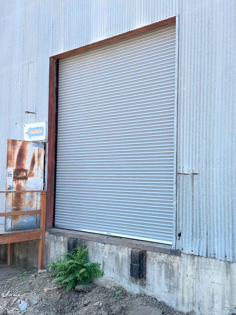 Industrial metal building with a white commercial garage door in Lane County, Oregon