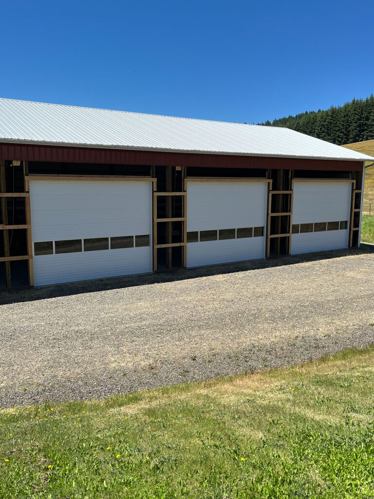Multi-bay building with white commercial sectional garage doors in Lane County, Oregon