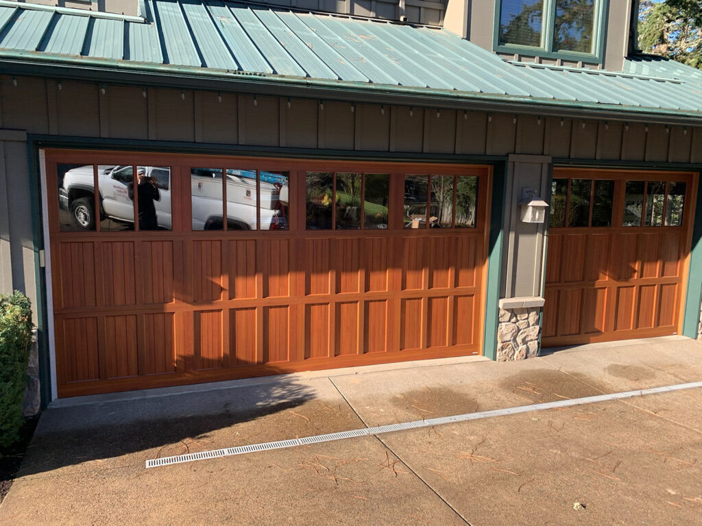 Stained wood carriage-style garage door with windows on a Eugene home