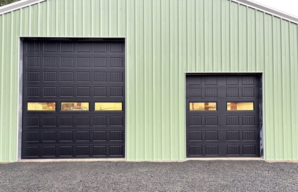 Dark commercial garage doors on a green steel building in Lane County, Oregon