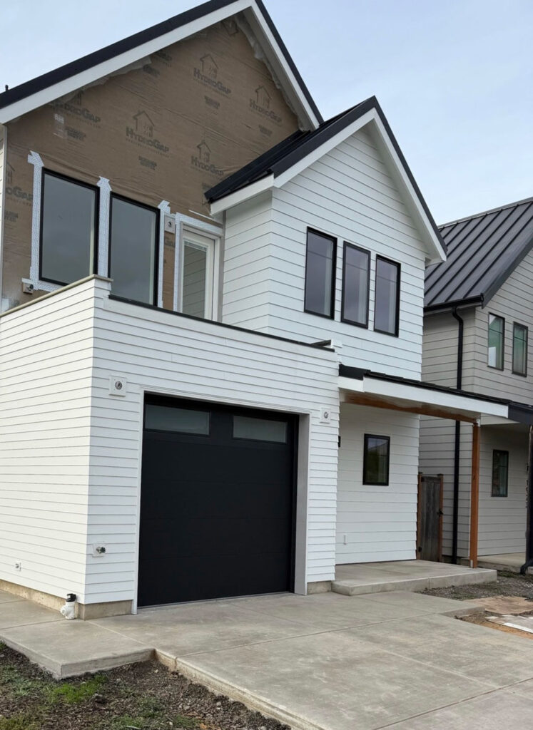 Modern two-story home with a dark residential garage door in Eugene, Oregon