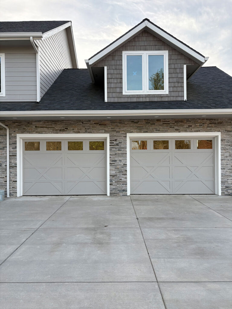 Carriage-style double garage doors with windows and stone accents on a Eugene home
