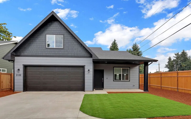 Two-story home with a dark double garage door and landscaped yard in Eugene, Oregon