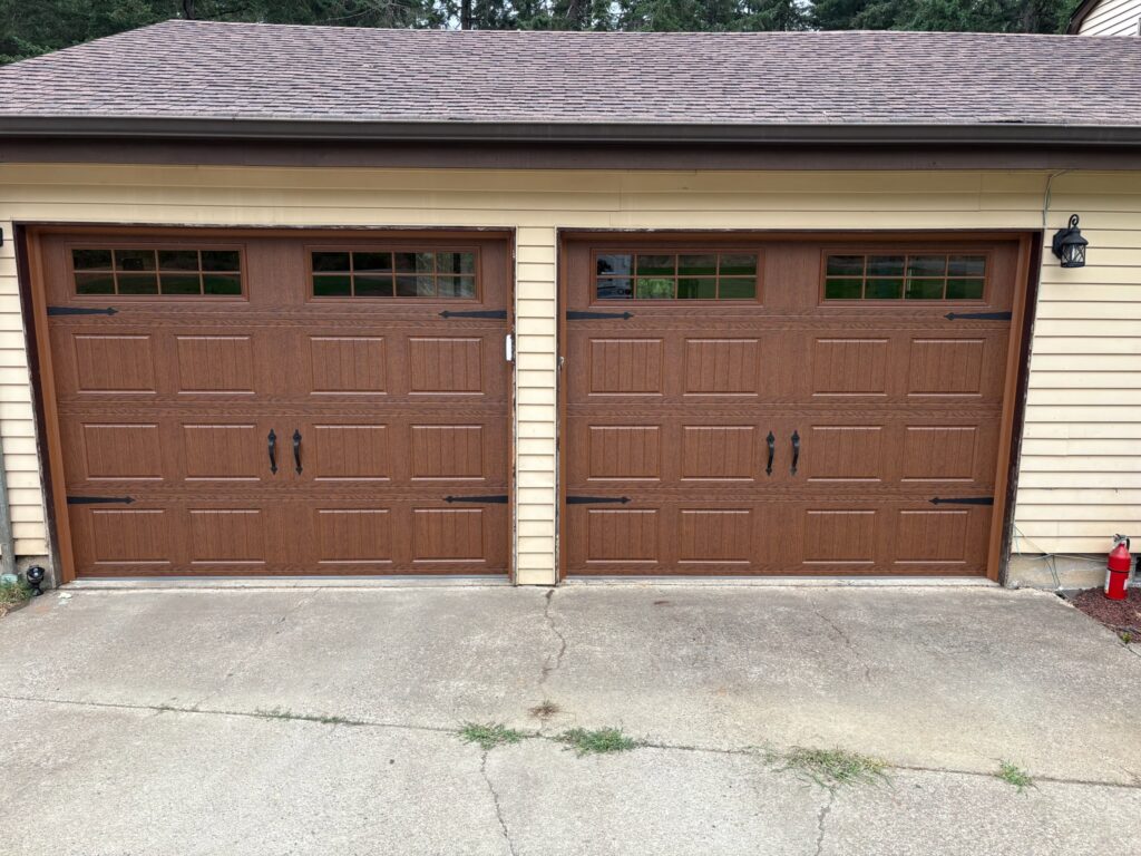 Carriage-style custom garage doors with woodgrain finish on a home in Eugene, Oregon
