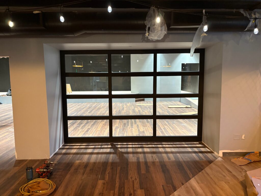 Full-view glass commercial garage door seen from inside a unit being fitted out in Eugene, Oregon