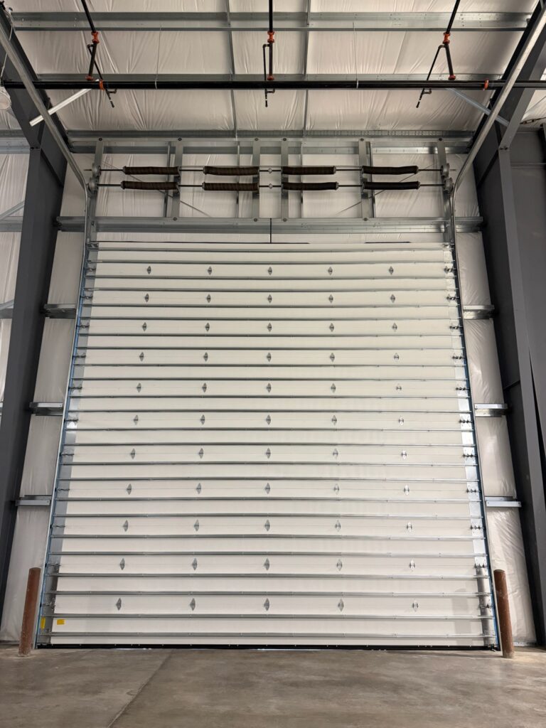 Looking up at a large industrial garage door from inside a steel building in Lane County, Oregon