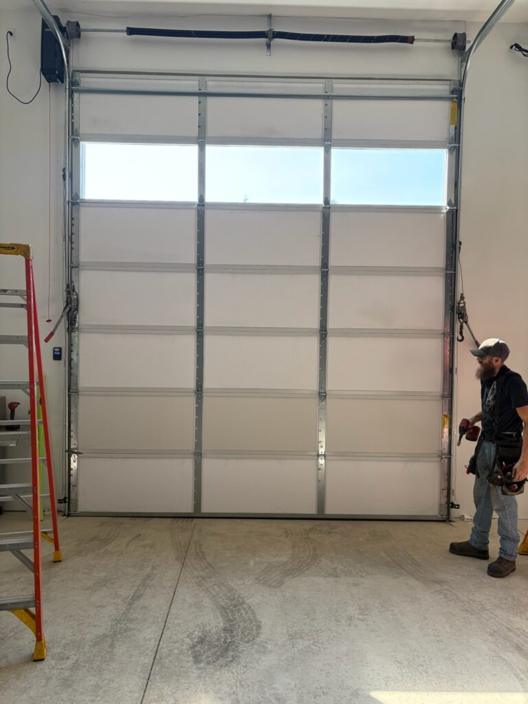 Crawford Windor technician inside a building beside a newly fitted commercial garage door, Eugene, Oregon